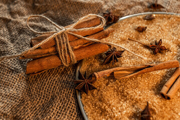 A bunch of cinnamon sticks, on cane sugar, with anise stars. Against the background of burlap.