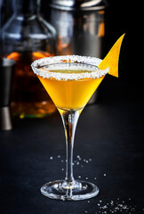 Sidecar, yellow cocktail with cognac, liqueur, lemon juice and ice. Black background, steel bar tools, copy space