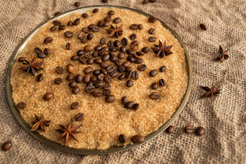 Coffee beans on brown sugar cane, lying on a bronze plate, against a background of coarse burlap. Background picture in brown tones