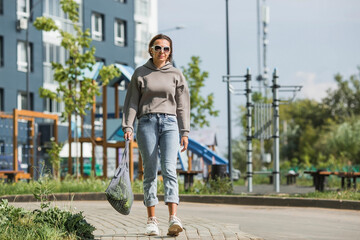 A modern stylish woman with a shopping bag, buying green vegetables against the background of the...