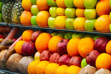 close-up of a shop window with selected fresh fruits: apples, oranges, coconuts, pineapples for a healthy lifestyle