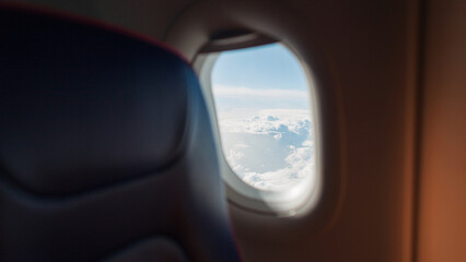 The interior of an airplane with a porthole flies in the sky with white clouds. Travel, business and transport, concept