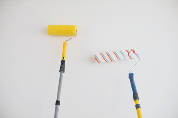 Two hands painting wall with paint roller, white color. Apartment renovation, repair, building and home concept. Copy space, banner. Tools for painting walls.