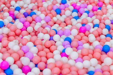 Background, close-up texture of many colored, multi-colored round plastic small balls on the playground for children's games. Photography, top view, copy space, childhood concept.