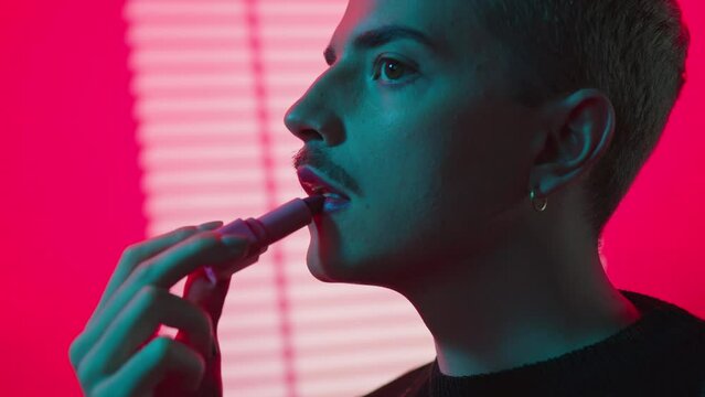 Young Blonde Gay Man With Mustaches Wearing Lipstick In Neon Pink Studio