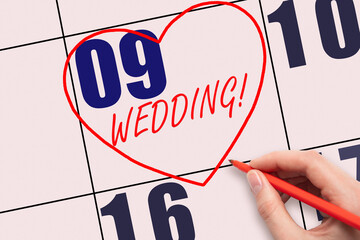 9th day of the month. Hand writing text WEDDING and drawing a red heart on a pink calendar date.