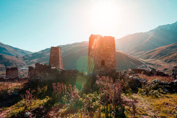 Old Ossetian battle towers in the rays of the warm morning sun in the misty mountains. Upper Fiagdon. North Ossetia, Russia - 569677448