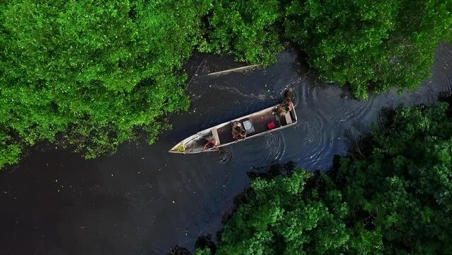 aerial view amazon native family on boat in river and jungle traveling on amazon river
