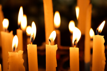 Close-up of several candles lit inside a church. Concept of religion, customs, beliefs and prayers.