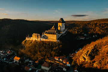 Naklejka premium Aerial view of gothic Royal Karlstejn Castle with Czech crown jewels,Czech Republic.Most popular Czech castle at sunset.Amazing historical monument in central Europe.Czech landmark,tourist attraction