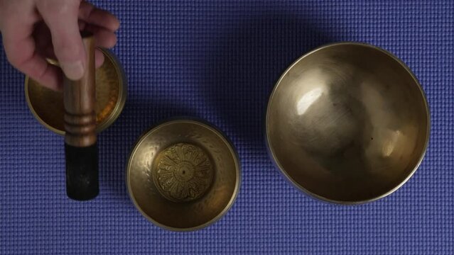 sound healing with a set of Tibetan singing bowls, top view with a mallet and hands of a senior male - audio