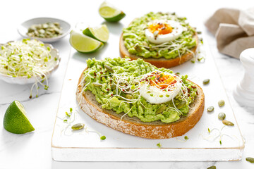 Avocado toast with boiled egg, seeds and sprouts on white background. Healthy diet food