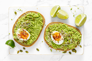 Avocado toast with boiled egg, seeds and sprouts on white background. Healthy diet food. Top view