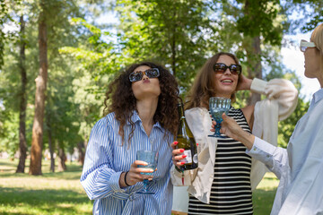 Fototapeta premium Art picnic in spring drinking wine, laughing, taking pictures on polaroid and having a great time with friends having delicious snacks 