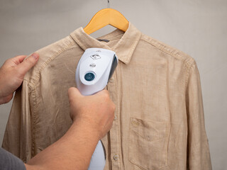 In hand Steamer for clothes. A shirt is ironed with a portable iron. Iron for ironing clothes.