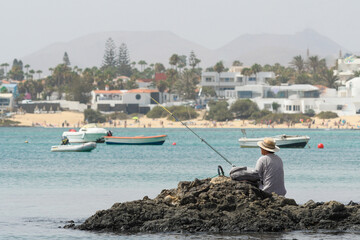 Fototapeta na wymiar Fisherman fishing on the beach of Corralejo