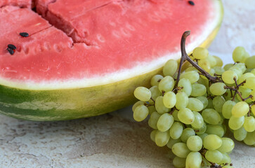 A bunch of ripe juicy grapes and cut watermelon on an abstract background