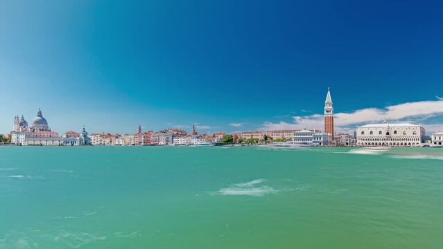 Venice panoramic timelapse with the Giudecca Island, the Madonna della Salute Church, Doge's Palace, St. Marc Square seen from the bell tower of the St. George. Blue cloudy sky at summer day