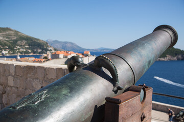 Two dolphins as a detail of an historic canon at the ancient Fort Livrijenac with view to the old town of Dubrovnik, Croatia in blurred background