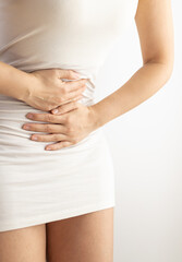Woman touching her stomach on a white background. Abdominal pain and other stomach ailments.