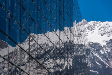 Glasfassade mit Spiegelung, schneebedeckte Berge