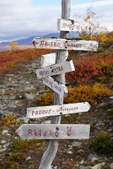 Old signpost for walking trails in autumn colored mountain area close to Abisko in Sweden. All words are names of places except kanjon=canyon, offerkullen=sacrificial hill