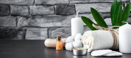 Wellness accessories on gray stone background. Towel, candles and aromatic salt.