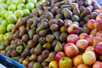 Ripe green pears and red apples on counter at market. Autumn harvest
