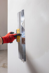 An even layer of putty on the wall for leveling - the work of a finisher in the interior