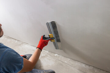 An even layer of putty on the wall for leveling - the work of a finisher in the interior