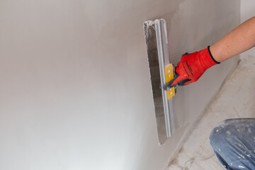 An even layer of putty on the wall for leveling - the work of a finisher in the interior
