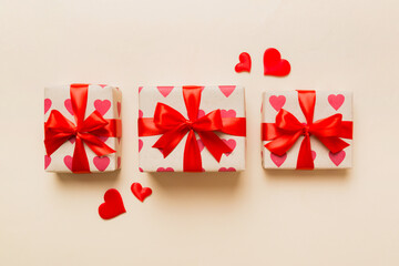 Top view photo of valentine day decorations gift box with red ribbon bow on colored background. Holiday gift boxes with top view