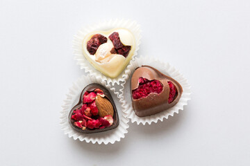 chocolate sweets in the form of a heart with fruits and nuts on a colored background. top view with space for text, holiday concept