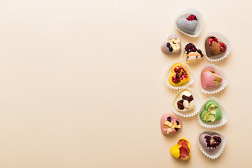 chocolate sweets in the form of a heart with fruits and nuts on a colored background. top view with space for text, holiday concept