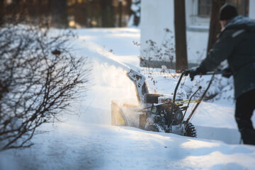 Process of removing snow with portable blower machine, worker dressed in overall workwear with gas...