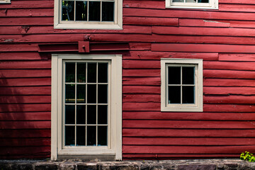 Exterior wood clad red barn wall with white framed windows
