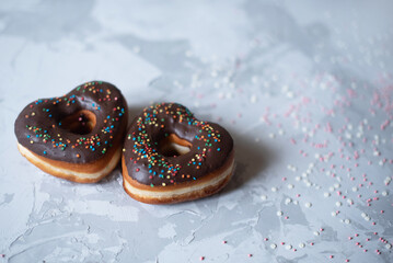 two donuts in a heartshape on a gray background on a white plate. Concept for Valentine's Day....