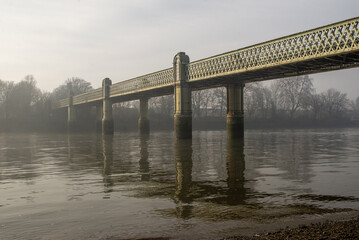 Riverfront in a foggy day in close to Chiswick Railway Bridge, an abandoned marina by the river Thames with soft waves and the banks
