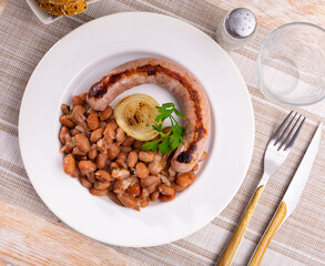 Traditional Catalan dish stewed beans with sausage on plate. Butifarra con alubias