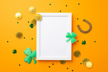 Saint Patrick's Day concept. Top view photo of empty photo frame horseshoe gold coins shamrocks and trefoil shaped confetti on isolated orange background with copyspace