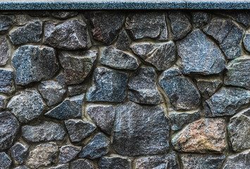 Texture of a stone wall, granite stone wall background, stacked pieces stones