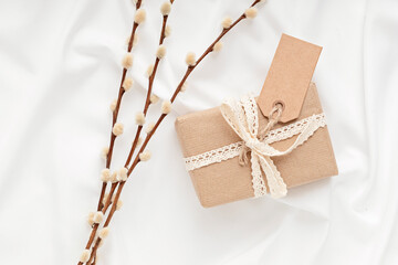 Gift box in craft paper with tag and natural decorations, creative and zero waste holidays present wrapping. Womens day, mothers day, easter greeting concept. Top view, flat lay, mockup