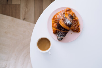 Flat lay cup of cappuccino and croissants on the white coffee table in room