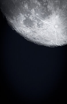 Tycho crater surrounded by smaller meteor craters. Vertical image of the craters on the moon filling the upper right hand of the photo against a black background. Copy space.