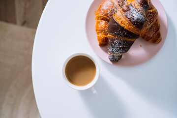 Flat lay cup of cappuccino and croissants on the white coffee table in room with beautiful sunlight