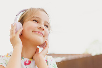 Close-up little cute girl laughing happily enjoying listening to music in headphones and phone...