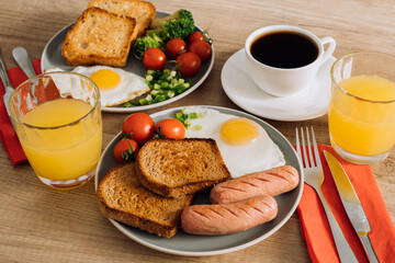 Grilled sausage and whole wheat toast with fried egg and cherry tomatoes, English breakfast with cup of black coffee and orange juice