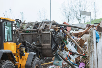 Heavy construction machine, front end loader moving along recycling center area, close up view. Waste management industry concept.