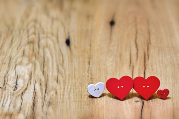 Two large red button hearts and two small ones on a wooden background in a rustic style. The concept of diversity, warmth and love in the family on Valentine's Day. background with copy space.