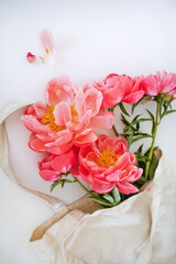 Bunch of pink peonies in craft bag, top view, white background 
